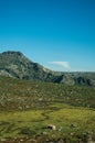 Lonely small house on green fields and rocky landscape Royalty Free Stock Photo