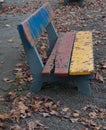 Lonely square bench with autumn leafs by the floor