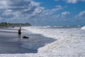 Lonely teenager standing on the beach near a large stone boulder during a storm