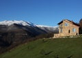 Lonely stone house on the hill on the background of snowy mountains, clear blue sky, horizontal Royalty Free Stock Photo