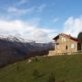 Lonely stone house on the hill on the background of snowy mountains, square Royalty Free Stock Photo