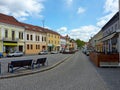 A lonely street of the Moravian city at daytime, with a tower, houses, trees and cars