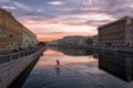 Lonely sup surfer moves along the Fontanka river at dawn