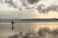 Lonely surfer at sunset in a desert beach