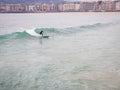 Lonely surfer is surfing on wawes at La Concha Beach in San Sebastian