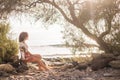 Lonely sweet beautiful middle age young woman sitting on the shore on a rock near the ocean. wave in background and peaceful place Royalty Free Stock Photo