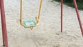 Lonely swing like symbol loneliness and boring. Solitariness empty playground swing on sand. Slow motion.