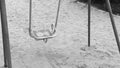 Lonely swing like symbol loneliness and boring. Solitariness empty playground swing on sand. Slow motion black and white