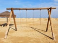 Lonely swing without sitting on an empty beach on a sunny, winter day. Royalty Free Stock Photo