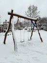 Lonely swings at empty children's playground covered with snow. Winter solitude. Prague.