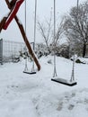 Lonely swings at empty children's playground covered with snow. Winter solitude. Prague.