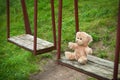 Teddy bear sitting on the swing. Loneliness concept.