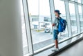 Lonely teen solo traveler with backpack standing in the empty airport passenger transfer hall in protective face mask and looking Royalty Free Stock Photo