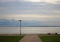 Lonely tiled road to empty seaside bench on a cloudy day