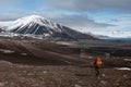 Lonely tourist hiking towards snow capped mountain in the Russian ghost town Pyramiden in Svalbard archipelago