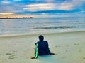 Lonely tourist relaxing on the beach and watching scenic sunset over blue sea Royalty Free Stock Photo