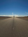 Lonely Traveler Standing on an Asphalt Empty Road in the Wilderness. Blue Sky. Royalty Free Stock Photo