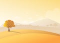 Lonely tree on a hill with mountains background in sunset view.Beauty autumn field and a tree scenery. Royalty Free Stock Photo
