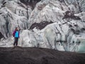 Lonely turist girl near a glacier on black vulcano sand
