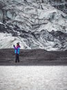 Lonely turist girl near a glacier taking pictures