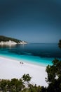 Lonely unrecognizable tourist couple under sun umbrella chill relax on beautiful idyllic pebble beach with crystal clear Royalty Free Stock Photo