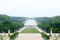A lonely view of Versailles park, France. The geometrical combination of green trees, grass areas and white statues.