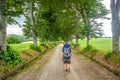 A lonely walker with backpack along a countryside road in center Italy, June 2019, with trees over him