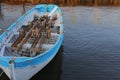 Lonely white-blue wooden boat with oars on the shore of a lake or river Royalty Free Stock Photo