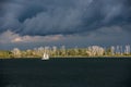 Lonely white sailing boat between dark water and depressing clouds