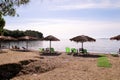 Lonely wicker sun umbrella at beach by sea. Natural bamboo sunshades, summer umbrella parasol, deck chairs, table, sun bed. Royalty Free Stock Photo