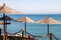 Lonely wicker sun umbrella at mediterranean beach by sea. Natural bamboo sunshades and summer umbrella parasol on ocean beach. Royalty Free Stock Photo