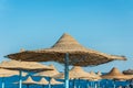 Lonely wicker sun umbrella at mediterranean beach by sea. Natural bamboo sunshades and summer umbrella parasol on ocean beach. Royalty Free Stock Photo