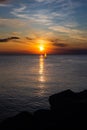 Lonely Wind surfer setting sail towards the dramatic and magnificent scenic sunset at the coast of the mediterranean sea in Royalty Free Stock Photo