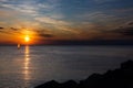 Lonely Wind surfer setting sail towards the dramatic and magnificent scenic sunset at the coast of the mediterranean sea in Royalty Free Stock Photo