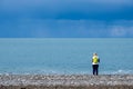 Lonely woman with a backpack stands by the sea. cloudy sky and cold water Royalty Free Stock Photo