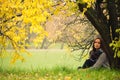 Lonely woman having rest under the tree near the water in a foggy autumn day Royalty Free Stock Photo