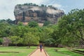 Lonely woman in headscarf walking to famous landmark Sigiriya rock, Sri Lanka. UNESCO world heritage site Royalty Free Stock Photo