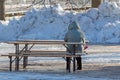 Woman in winter jacket sitting on a bench at a wooden table