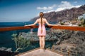 Lonely woman with long braid stands on viewpoint with ocean landscape Los Gigantes cliifs. Rocky coastline. Deep blue