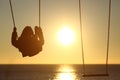 Lonely woman silhouette swinging at sunset on the beach Royalty Free Stock Photo