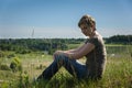 Lonely woman sitting with her back on green field Royalty Free Stock Photo