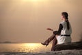 Lonely woman sitting on lake coast