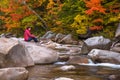 Lonely woman sitting on a rock along a mountain river in autumn Royalty Free Stock Photo