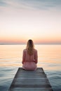 lonely woman sitting on wooden pier at lake or sea, serenity and calmness, solitude concept