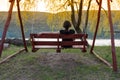 Lonely woman swinging on the swing back. On background of river and hill Royalty Free Stock Photo