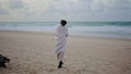 Lonely woman walking beach on cloudy day. Calm tourist watching ocean waves rear Royalty Free Stock Photo