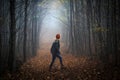 Lonely woman walking on footpath in dark foggy mystery forest