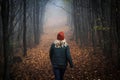 Lonely woman walking on footpath in dark foggy mystery forest