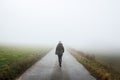 Lonely woman walks on empty road in fog Royalty Free Stock Photo