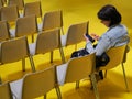 Lonely woman watching smartphone in empty seats room